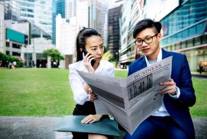 Two people reading newspaper