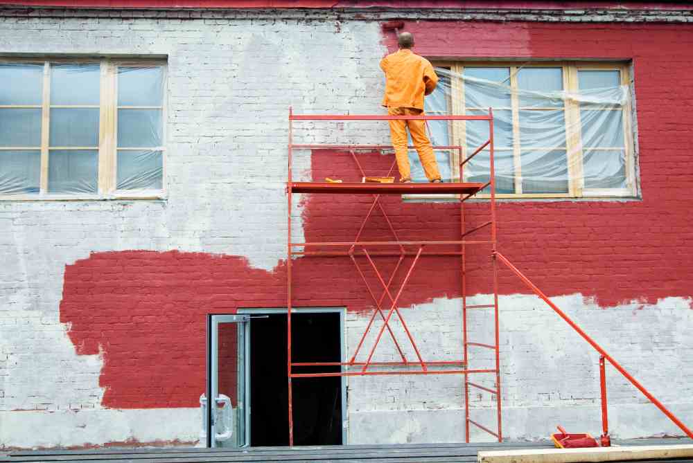 A house renovation contractor painting outside a building (illustration)