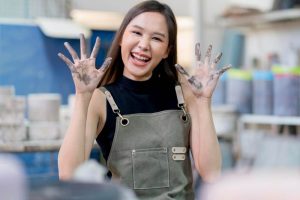 A warehouse worker smiling, she has dirt in her hands.